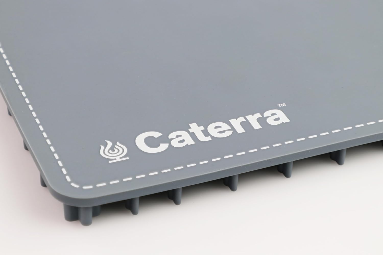 Corner detail of the slate blue warming mat showing the Caterra logo, dashed border print and silicone feet