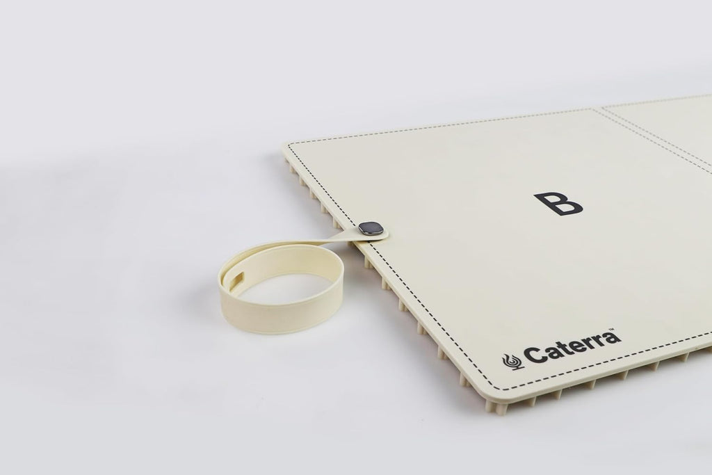Cream warming mat with its magnetic silicone roll-up strap detached, showing heating zone B and the Caterra logo